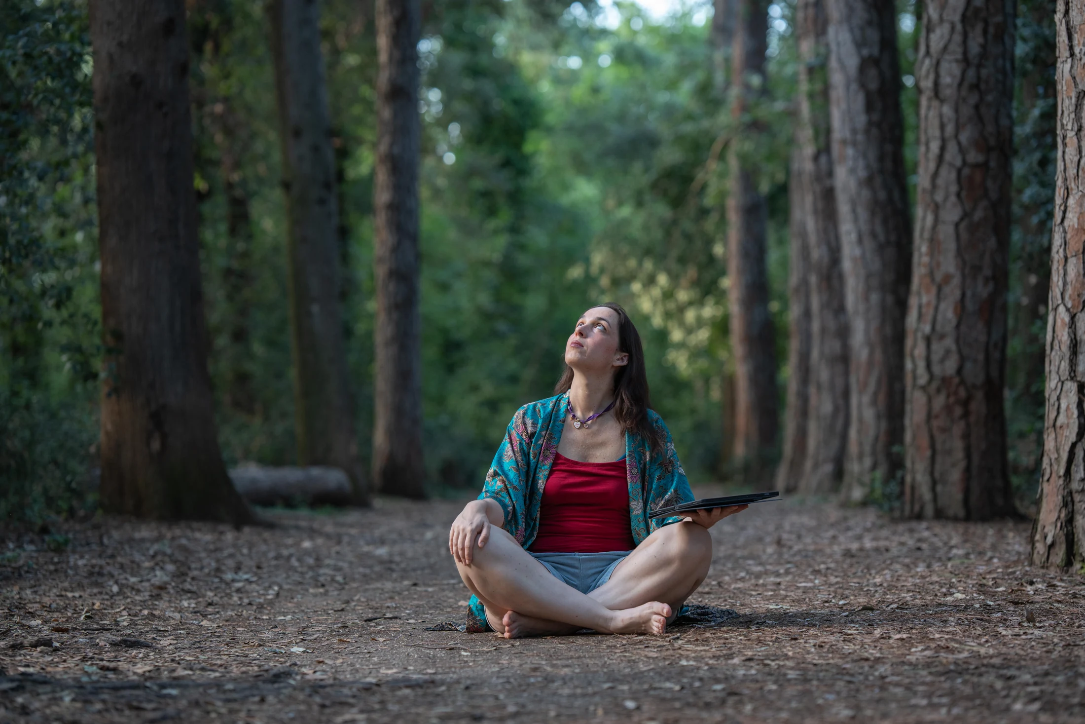 Federica Nardi seduta nel bosco guarda verso l’alto